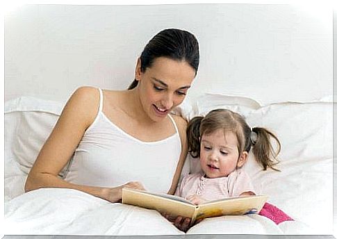 Mother sitting and reading with her daughter in bed