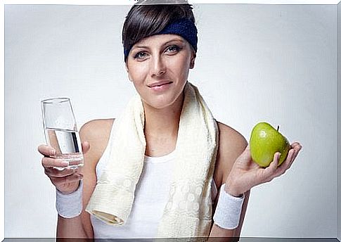 Woman holding a glass of water and an apple