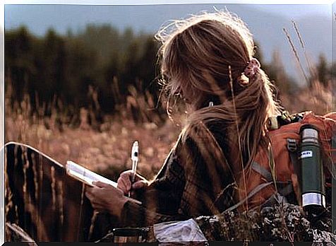 Woman writing diary on a meadow