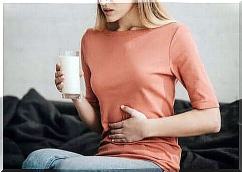 Woman takes care of stomach with a glass of milk in hand