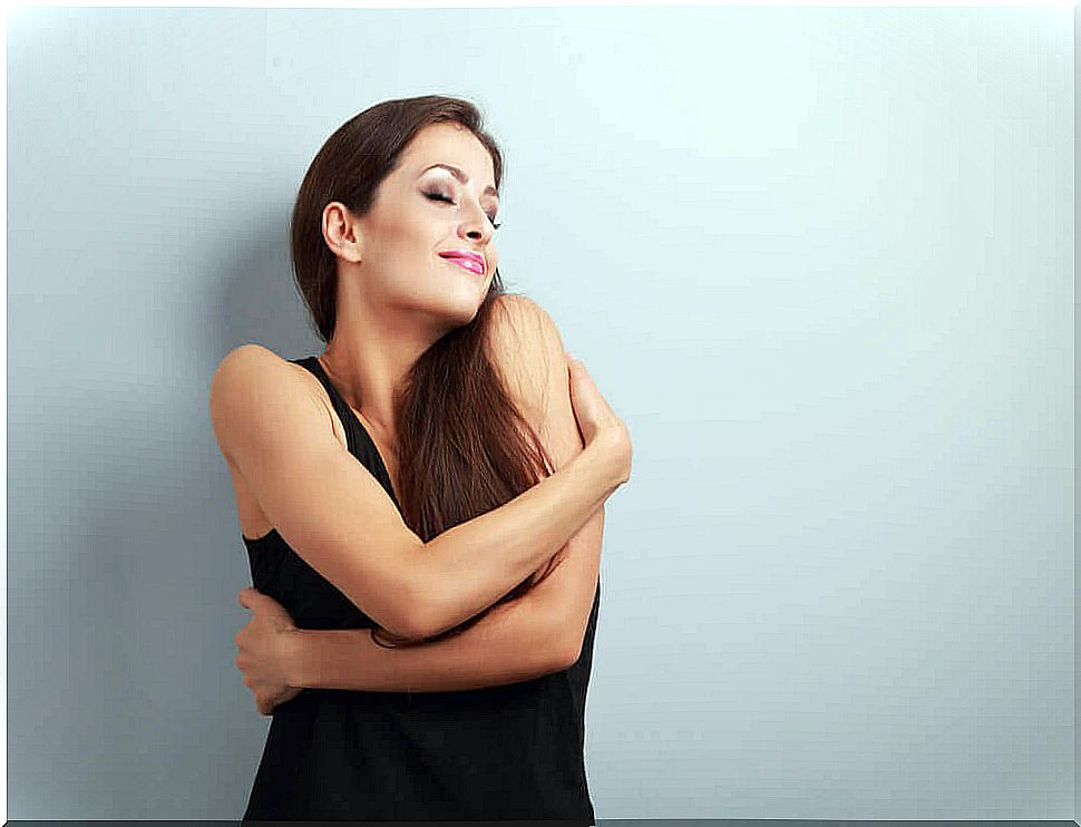 Smiling woman is happy with herself and hugs herself