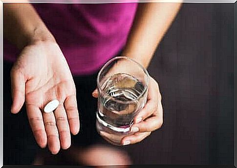 Woman with pill and water in hands